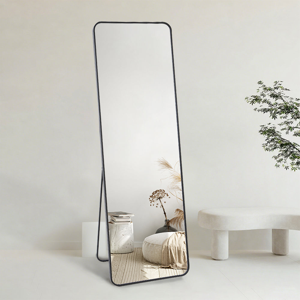 Black full-length floor mirror in bedroom